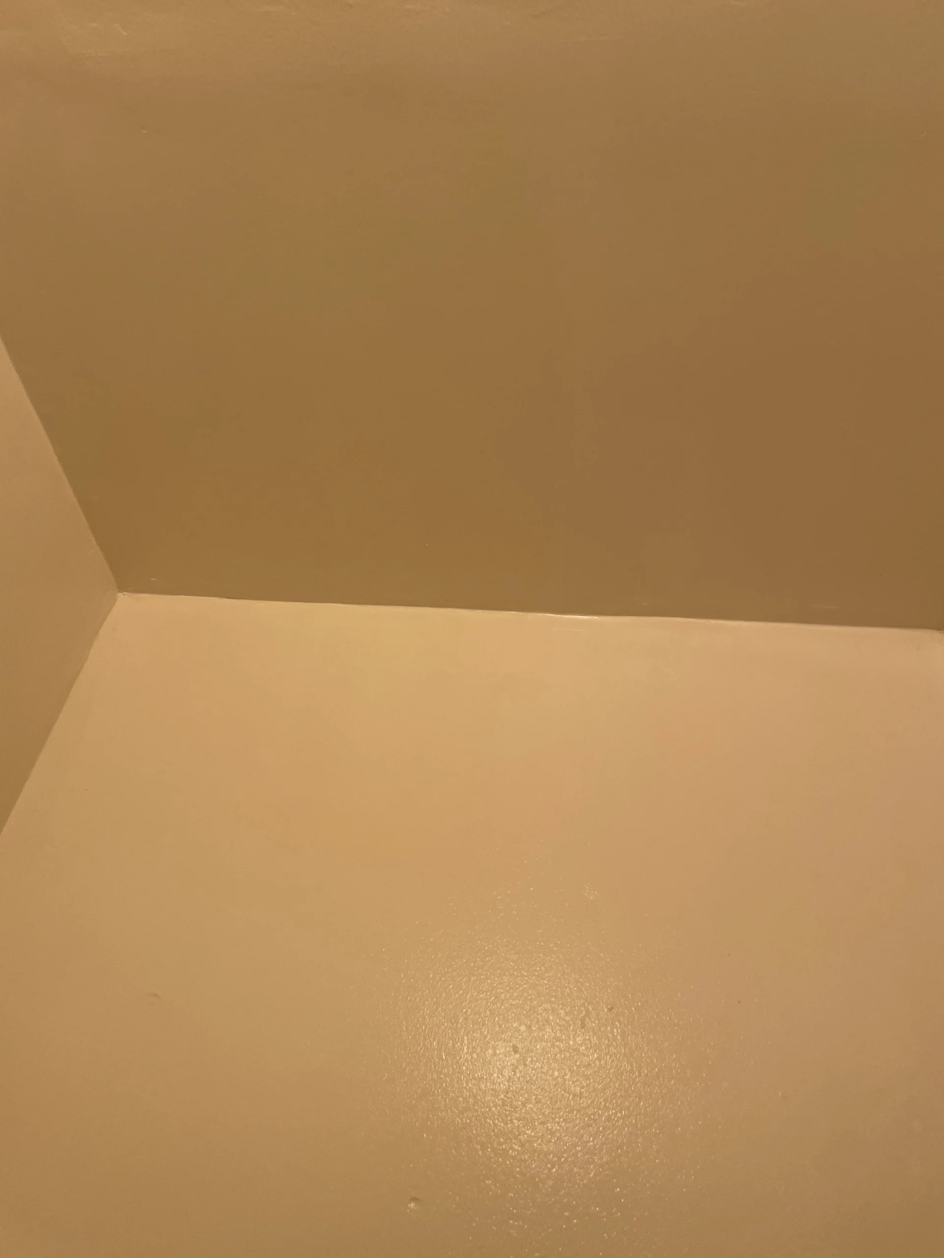A plain, light beige wall and ceiling corner with a smooth, clean surface finish.